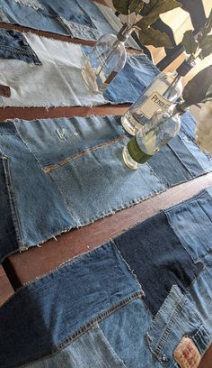 several pairs of jeans are stacked on top of each other with a bottle in the middle