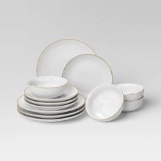 a white and gold dinner set with four plates, two bowls and one plate on the side