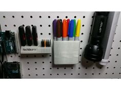 several pens and pencils are placed on a pegboard