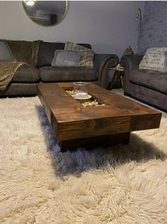 a coffee table sitting on top of a white rug in front of a gray couch