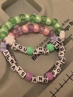 two bracelets with words and beads on them sitting on top of a table next to each other