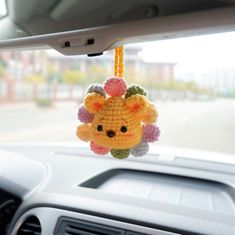 a crocheted giraffe hanging from the dashboard of a car