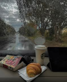 a cup of coffee and some pastries on a table in front of a window