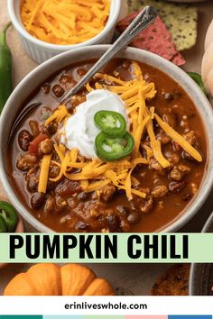 pumpkin chili in a bowl with sour cream and cheese on top, surrounded by other dishes