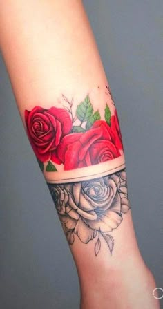 a woman's arm with red roses and leaves on the top half of it