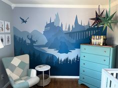 a room with a wall painted like a castle and trees on the walls, along with a blue dresser