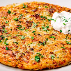 a close up of a pizza on a plate with sour cream and parsley sprinkled