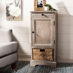 a living room with a gray chair and a wooden cabinet in the corner next to a white wall