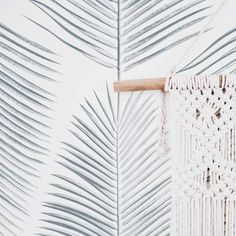 a white wallpaper with palm leaves on it and a piece of wood sticking out of the side