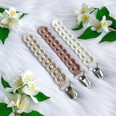 three pieces of crocheted hair clips laying on top of white fur with flowers in the background