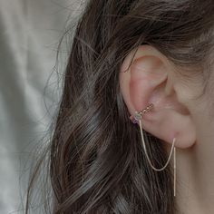 a close up of a person's ear with a chain attached to the side