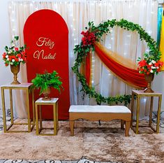 a couple of tables sitting next to each other with flowers on them in front of a red wall