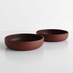 two brown bowls sitting on top of a white table