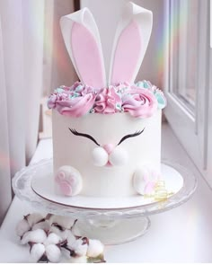 a white cake with pink frosting and bunny ears