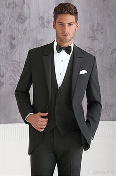 a man in a tuxedo poses for the camera with his hands in his pockets