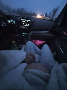 a person laying in the back seat of a car at night with their feet up