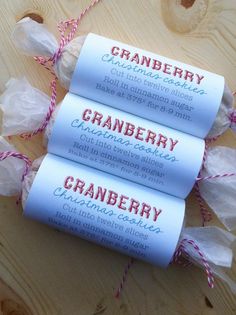 three rolls of cranberry candy sitting on top of a wooden table with twine