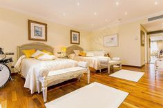 two beds in a room with hard wood floors and white furniture on either side of the bed