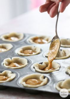 a person is dipping sauce into mini cupcakes on a baking sheet with a spoon