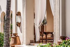 an outdoor patio area with white curtains and potted plants on the side of it