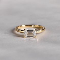 a yellow gold ring with an emerald cut diamond