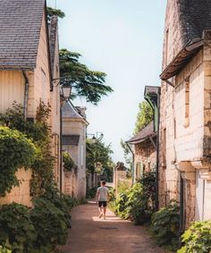 a person walking down an alley way between two buildings with ivy growing on the sides