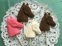 four chocolate horse lollipops on a lace doily with pink and brown ones