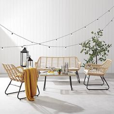 a table and chairs with yellow blankets on them in front of a string of lights