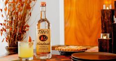 a bottle of alcohol sitting on top of a table next to pies and drinks