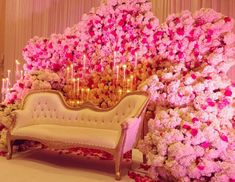 a couch sitting in front of a flower covered wall with candles on top of it