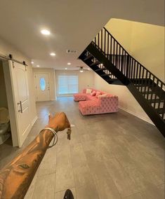 a living room filled with furniture and a stair case in front of a pink couch