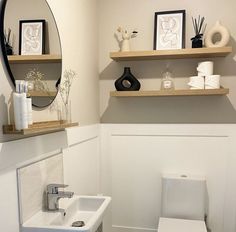 a white toilet sitting in a bathroom next to a sink and a wall mounted mirror