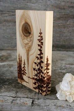 a wooden block with trees on it next to some rocks and a rock that has been carved into it