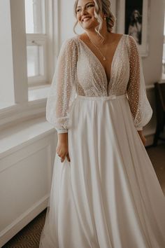 a woman in a white dress standing next to a window