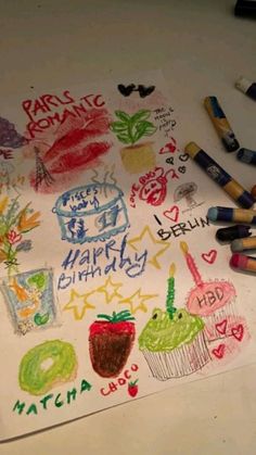 some crayons are laying on top of a sheet of paper with writing and drawings