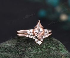 a pink diamond ring sitting on top of a green rock