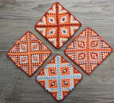 four orange and blue woven coasters sitting on top of a wooden table