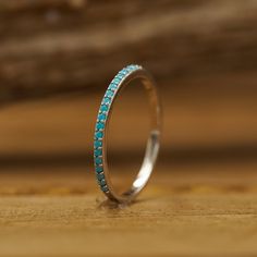 a white gold ring with blue stones on it sitting on a wooden table next to a piece of wood