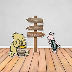 two winnie the pooh stickers sitting next to a wooden sign