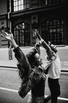 two people standing on the side of a road with their arms in the air