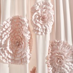 pink paper flowers are hanging on the curtain