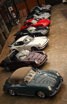 a row of cars parked next to each other on top of a cement floor in a building