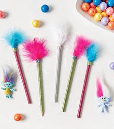 some candy sticks with different colored feathers and candies on the table next to them