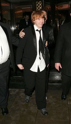 two men in tuxedos are walking down the street