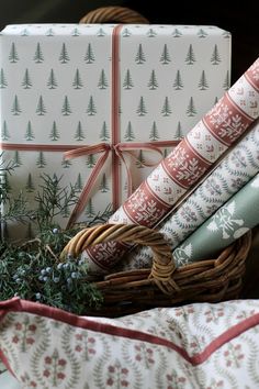 wrapped presents in wicker basket on table next to christmas tree wrapping paper and twine