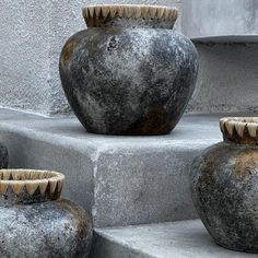 three large vases sitting on concrete steps