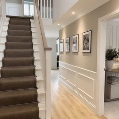 a hallway with stairs and pictures on the wall