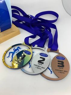 three medals and a ribbon on a white table with a blue award stand in the background