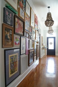 a hallway with pictures on the wall and a chandelier