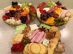 a variety of cheeses, crackers and meats arranged in baskets on a table